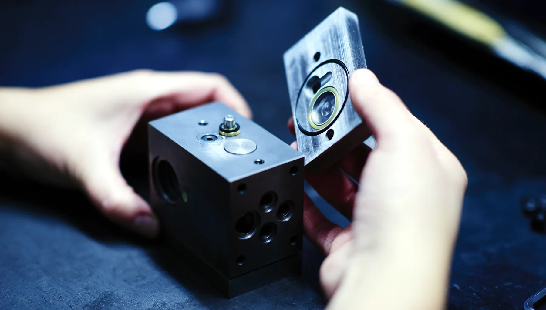 Händer som håller precisionshanterad hydraulkomponent i rostfritt stål med synlig cylinderborrning
